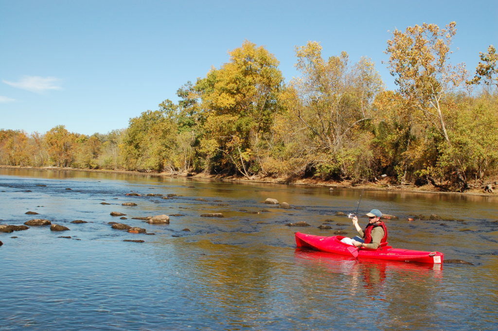 A man in a red kayak rafting along the New River