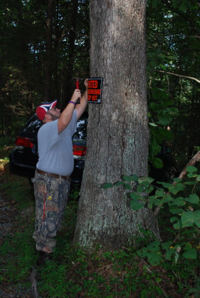 An image of a man nailing a sign to a tree