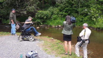 An image of a disabled person in a wheelchair fishing from a newly barrier free trail allowing for all accessibilities to the water