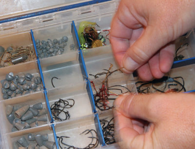 An image of a tackle box with organized fishing lures, weights and hooks