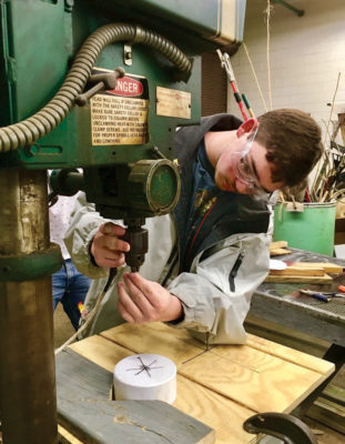 An image of a high school student using a drill to create the PVC nest bottom cap at an HCHS shop class; during this class 50 nesting boxes were made