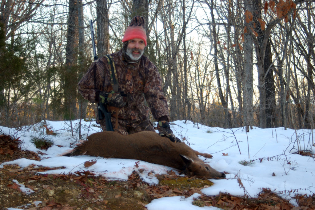 An image of a man posing with a deer he has killed in the snow