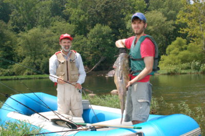 An image of two men and a flathead catfish
