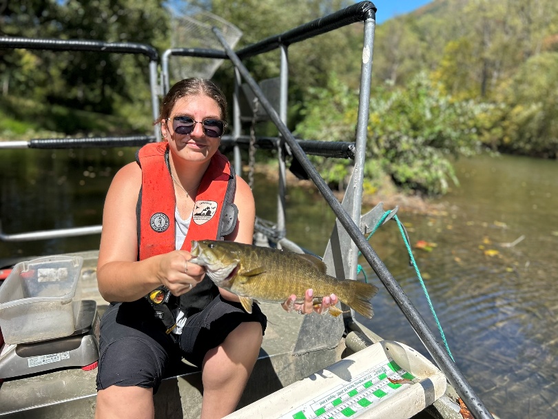 Angler on a boat holding a smallmouth bass from the Cowpasture River.