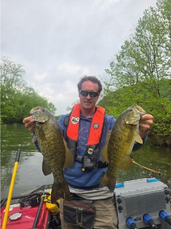 Angler on a boat holding two smallmouth bass from the North Fork Holston River.