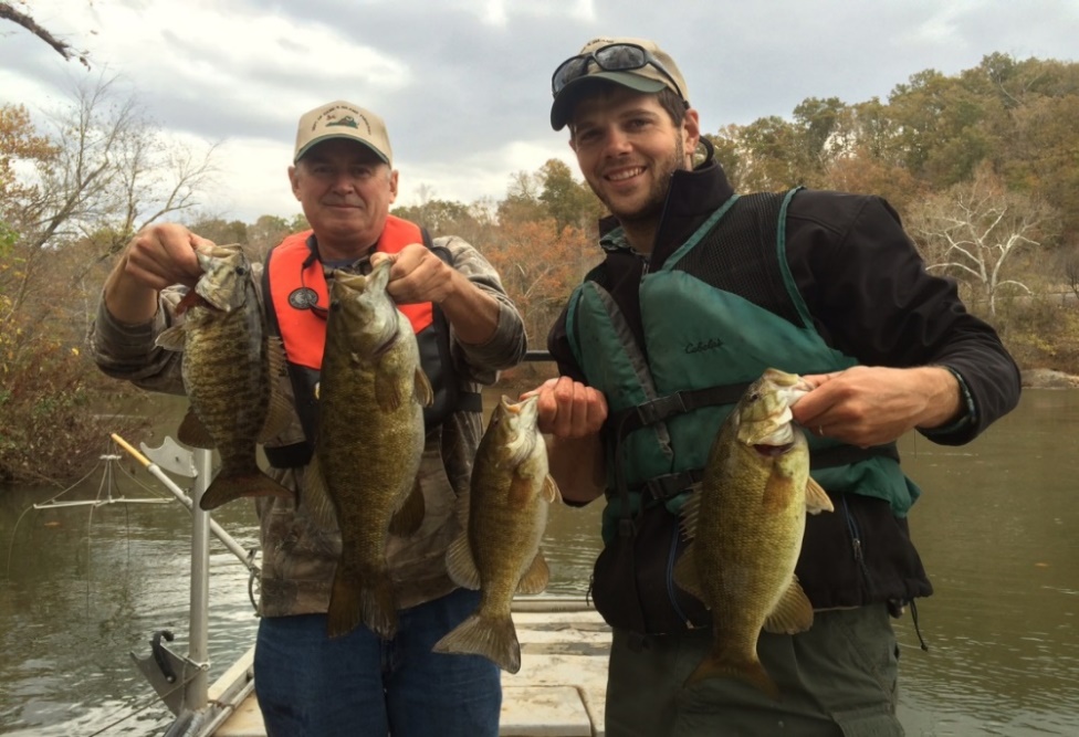 Two anglers on a boat holding smallmouth bass on the Staunton River.