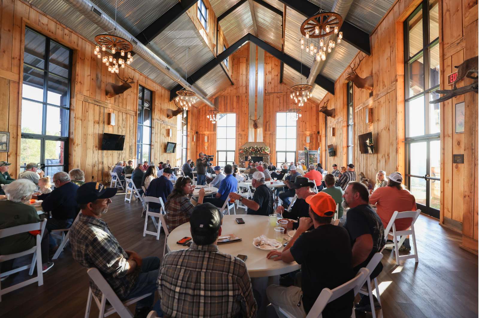 A large group of people gathered at tables for a meal in a large, open building.