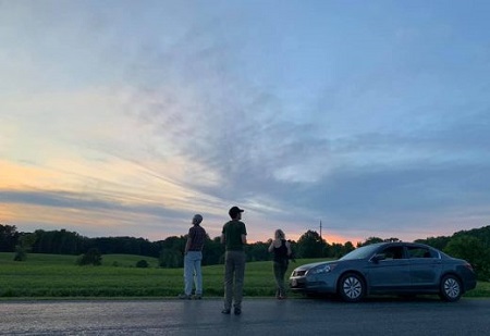 An image of a car in the sunset and a trio of people looking for nightjars