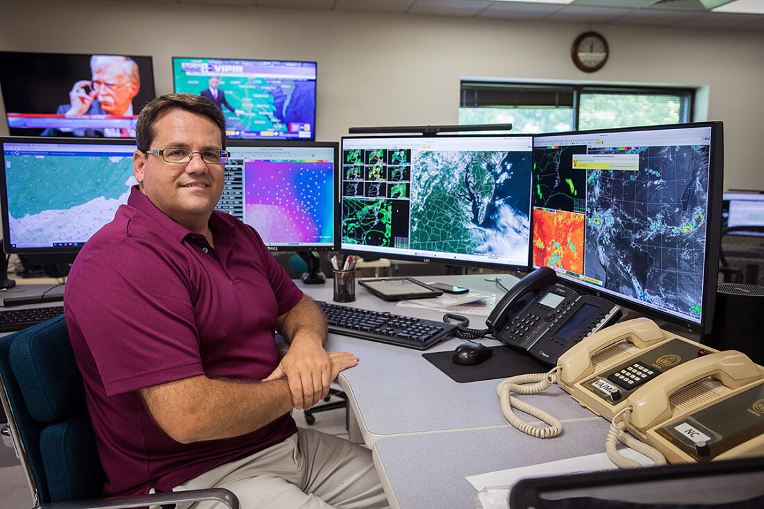 An image of NOAA's meteorologist in front of his NOAA weather service office workstation