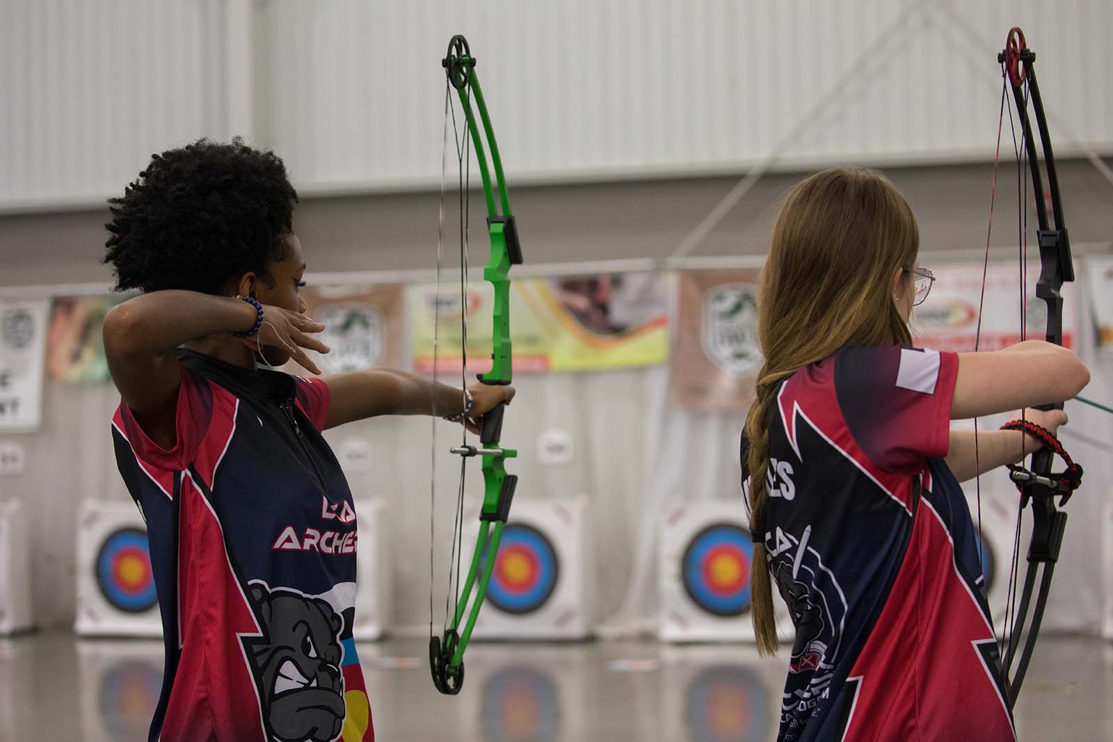 Two young archers shooting arrows at targets during a tournament