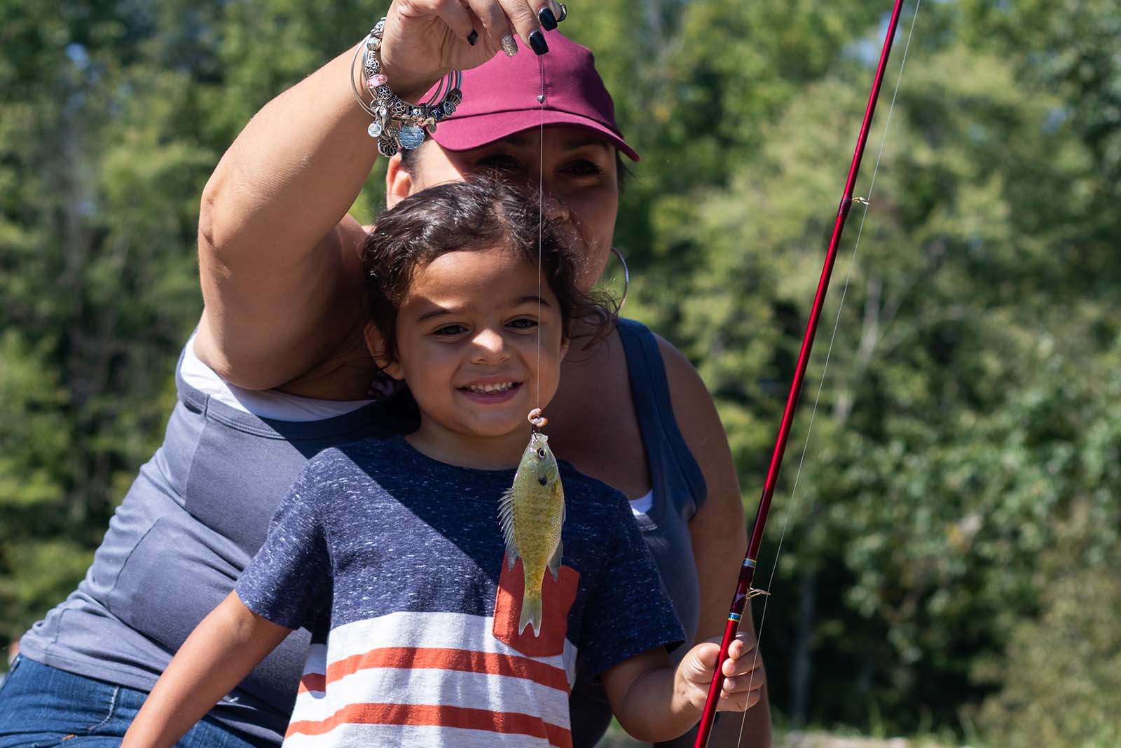 A mother and daughter smiling and holding up a fish on a line