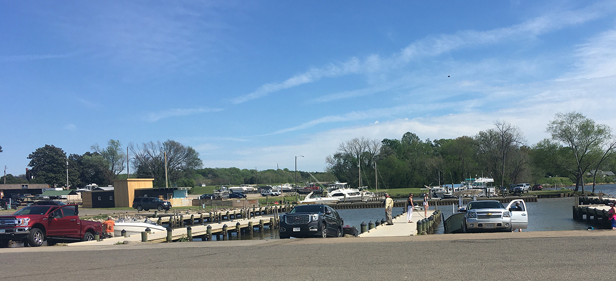 An image of multiple trucks going down boat ramps to place their boats into the water at a local marina