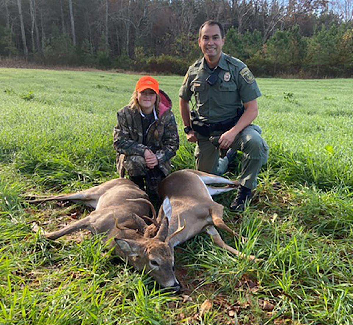 An image of CPO Cory Harbor and a young hunter posing in front of two dead deer