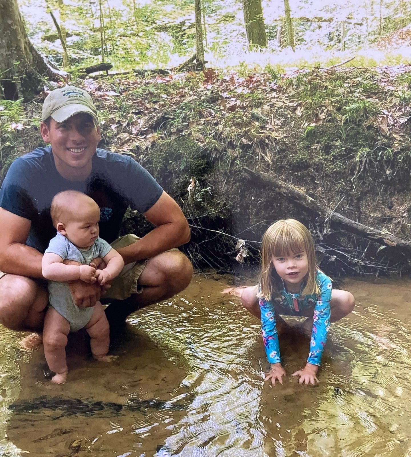 An image of two children and their father in a creek