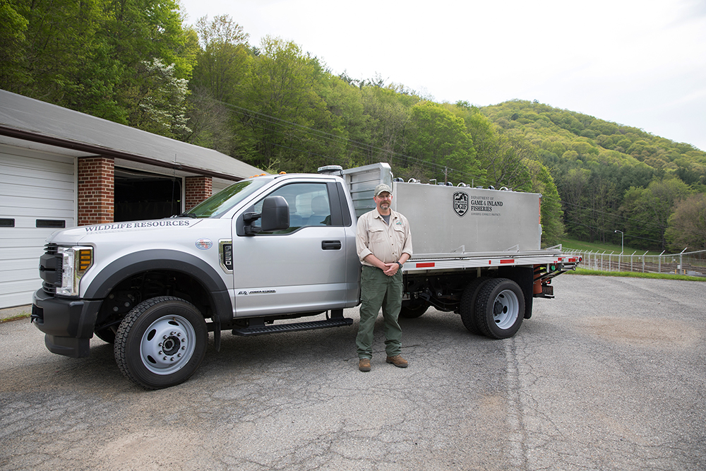 An image of a man in front of a hatchery transport truck