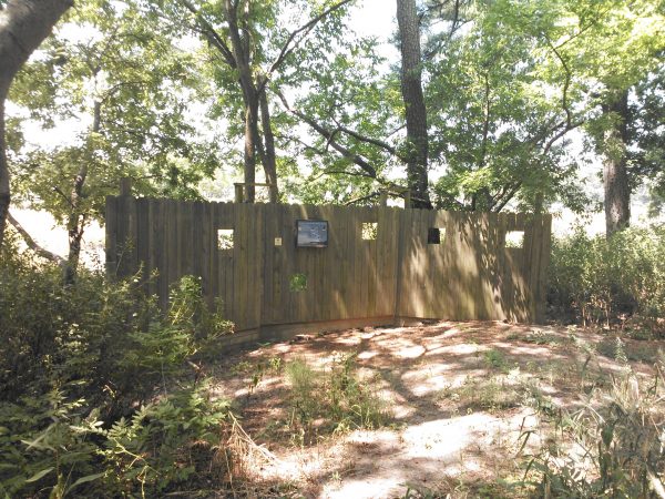 An image of a birding blind which resembles a wooden fence with holes cut in it for viewing which is located at the homestead trail