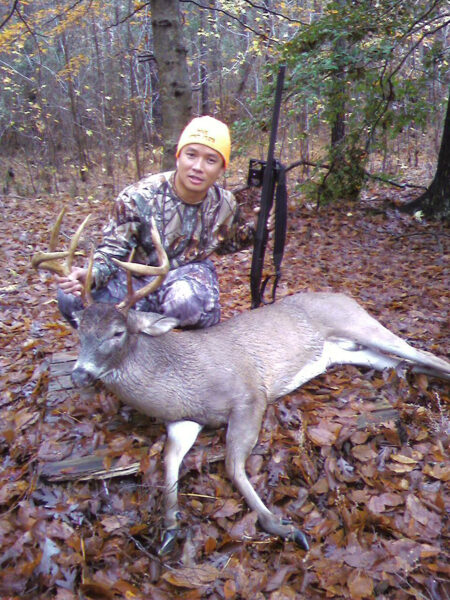 A man posing with a deer he has killed