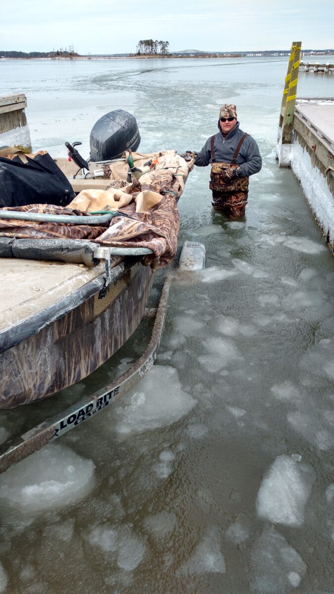 An image of a man in icy water helping dock a boat