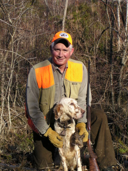 An image of a man with a orange visibility vest and hat alongside his English setter Gracie holding a Christmas Day Woodcock