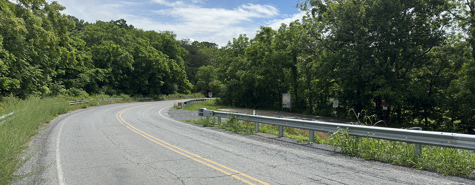 A photo of a road curving through trees.