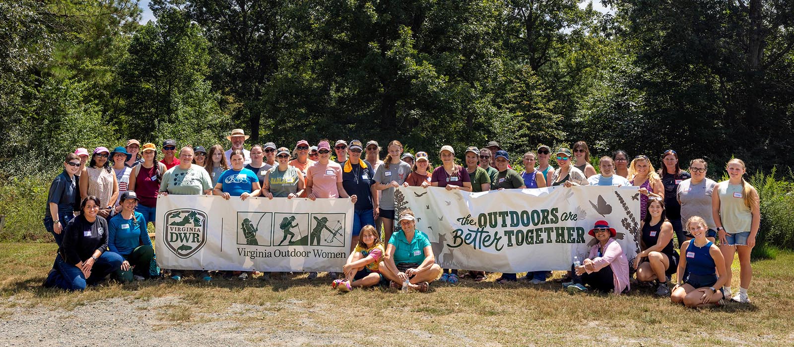 A photo of a group of women standing holding a banner that reads "The Outdoors Are Better Together."
