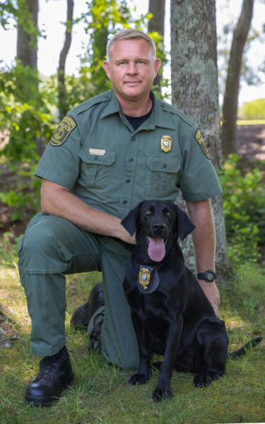 An image of Sky the black lab and her handler