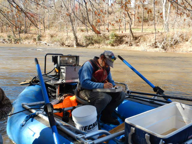 An employee on the electrofishing boat taking notes from the sampling of the day