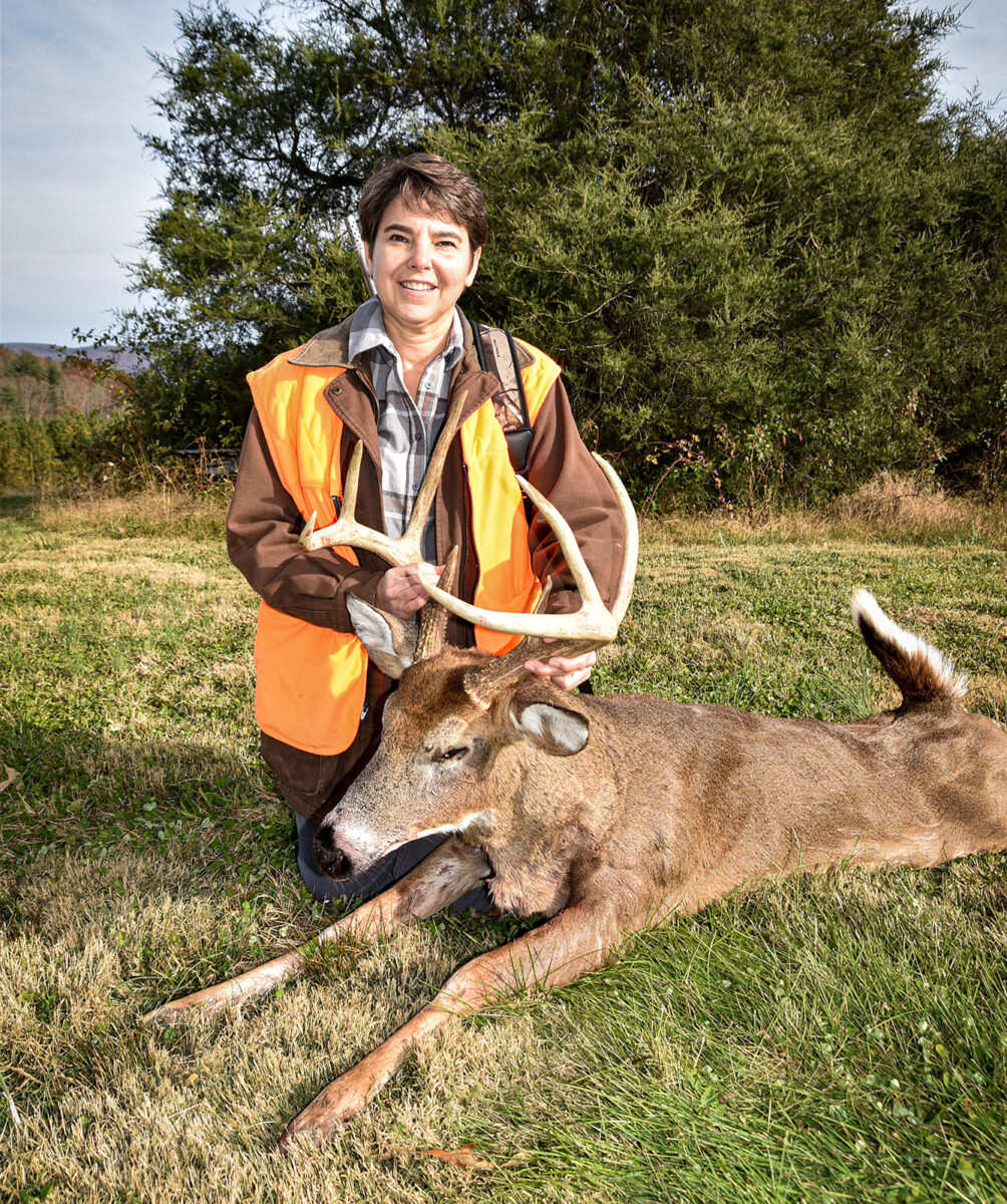 An image of Beth Leffel next to a three point buck that she has killed