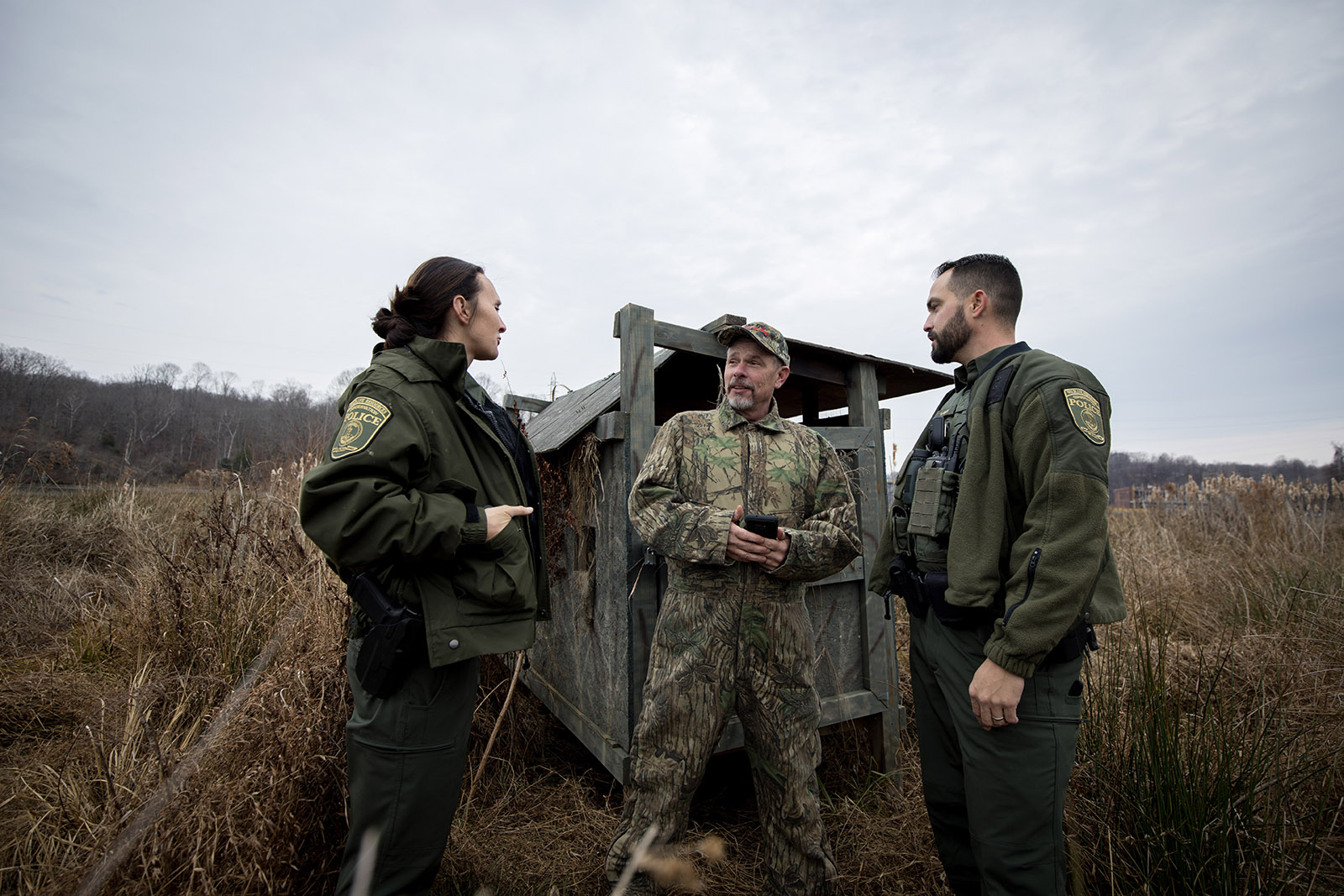 A photo of a female CPO in uniform and a male CPO in uniform talking with a hunter in camouflage.