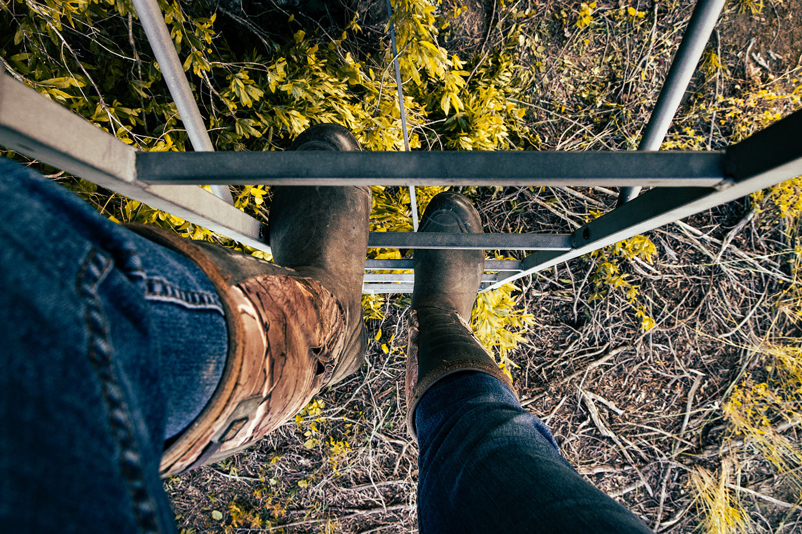 A close-up photo of booted feet climbing the ladder of a treestand.