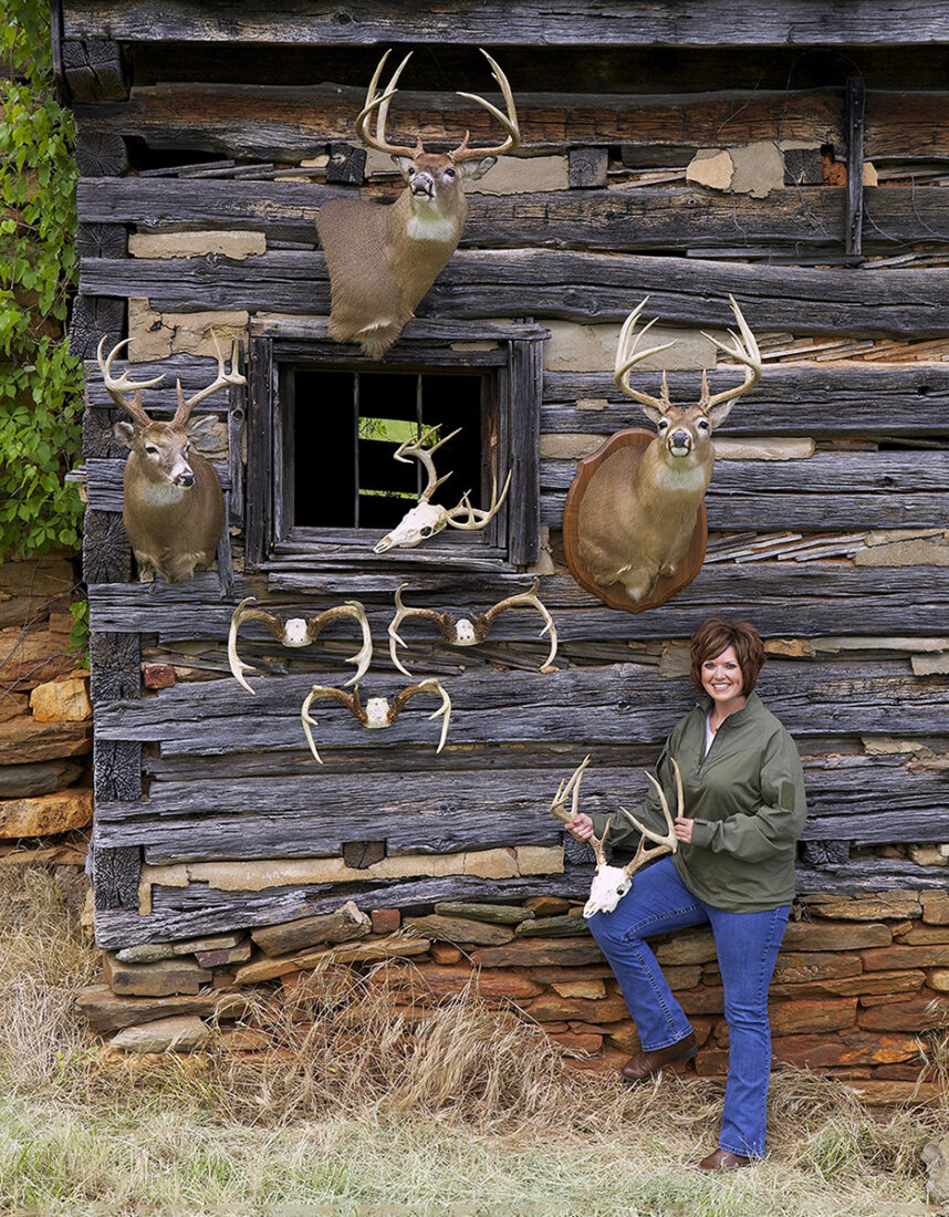 An image of a woman and all her hunting trophies