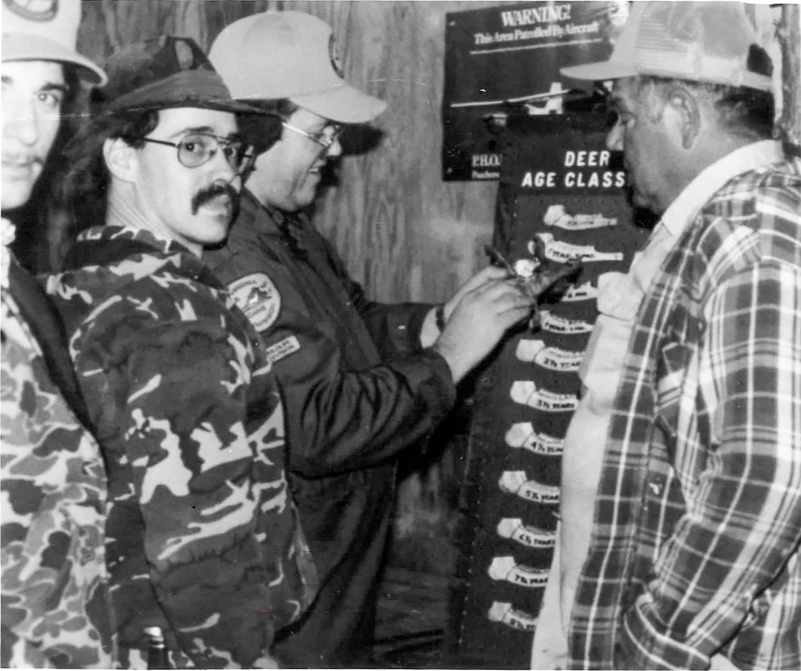 An old black-and-white image showing hunters measuring deer jawbones.