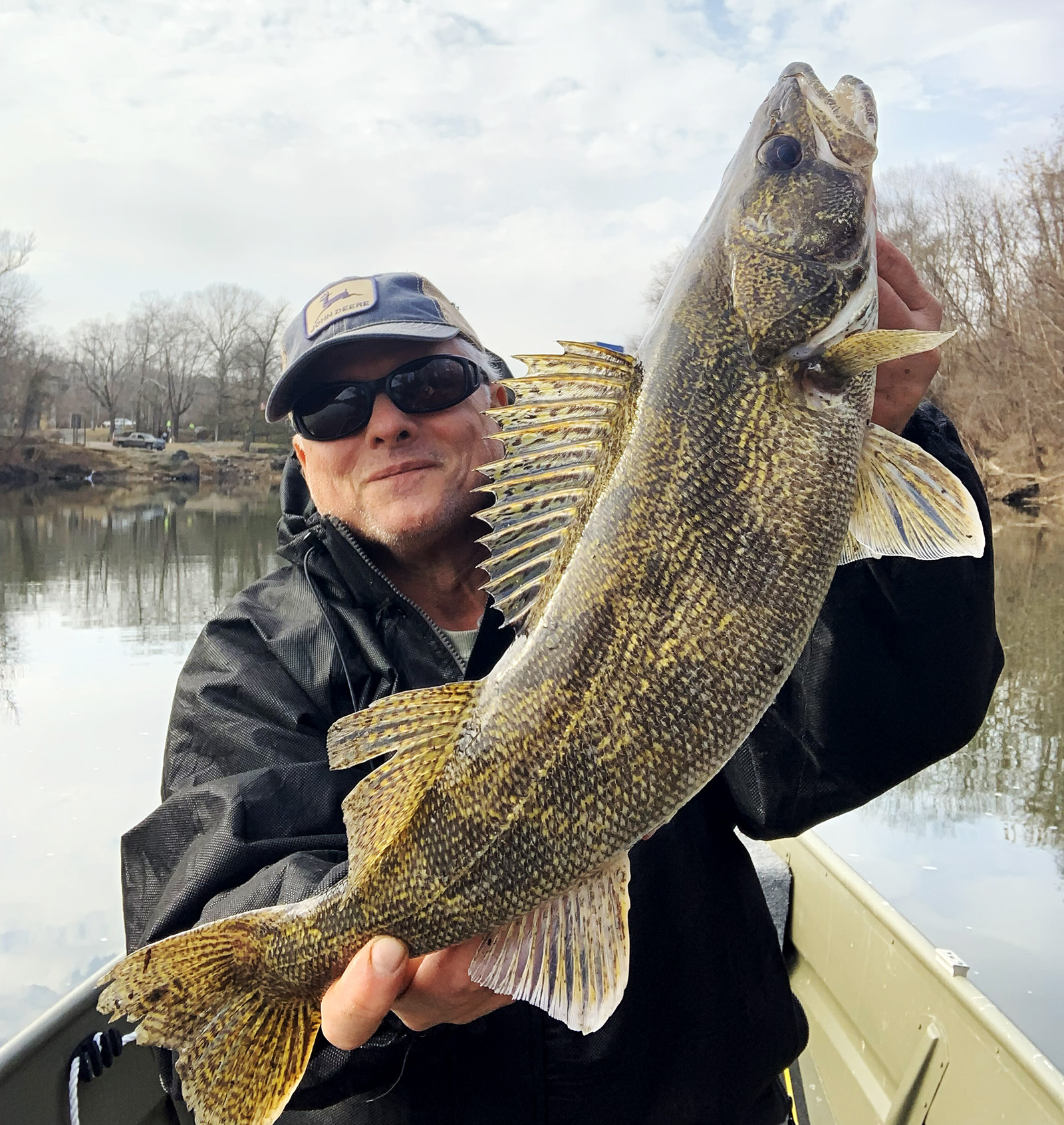 A man holding a large saugeye fish up and smiling.