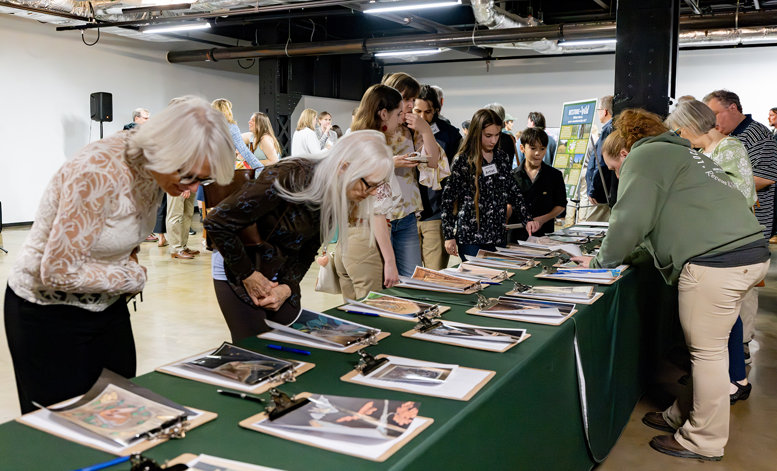 A photo of people standing around a table looking at clipboards.