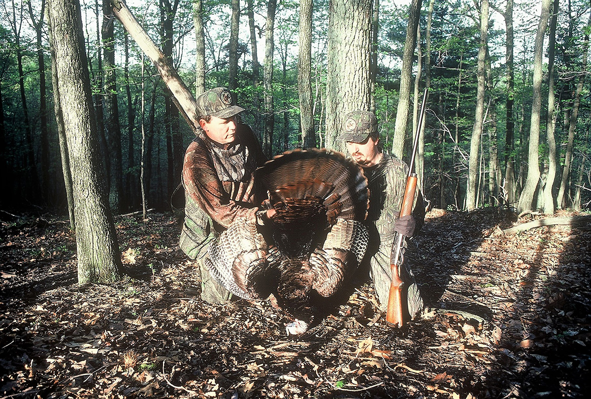 An image of a male turkey and the two hunters that shot it