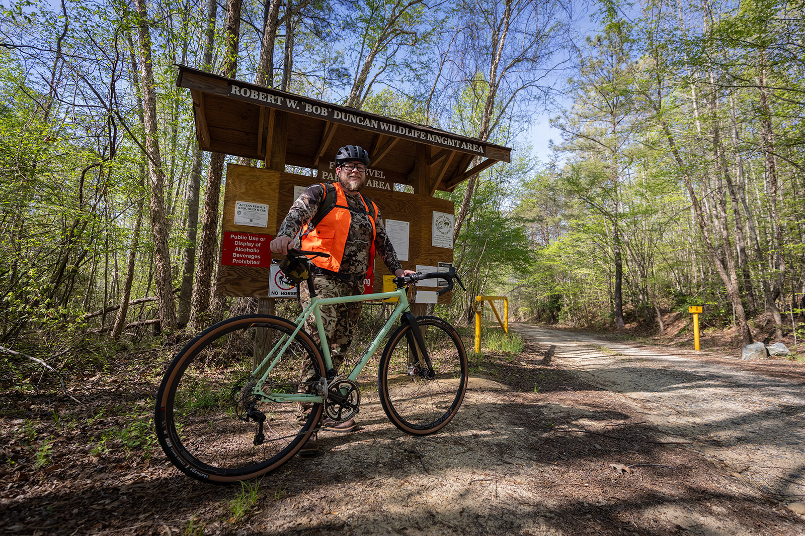 A photo of a man next to a bicycle in front of a Wildlife Management Area kiosk.