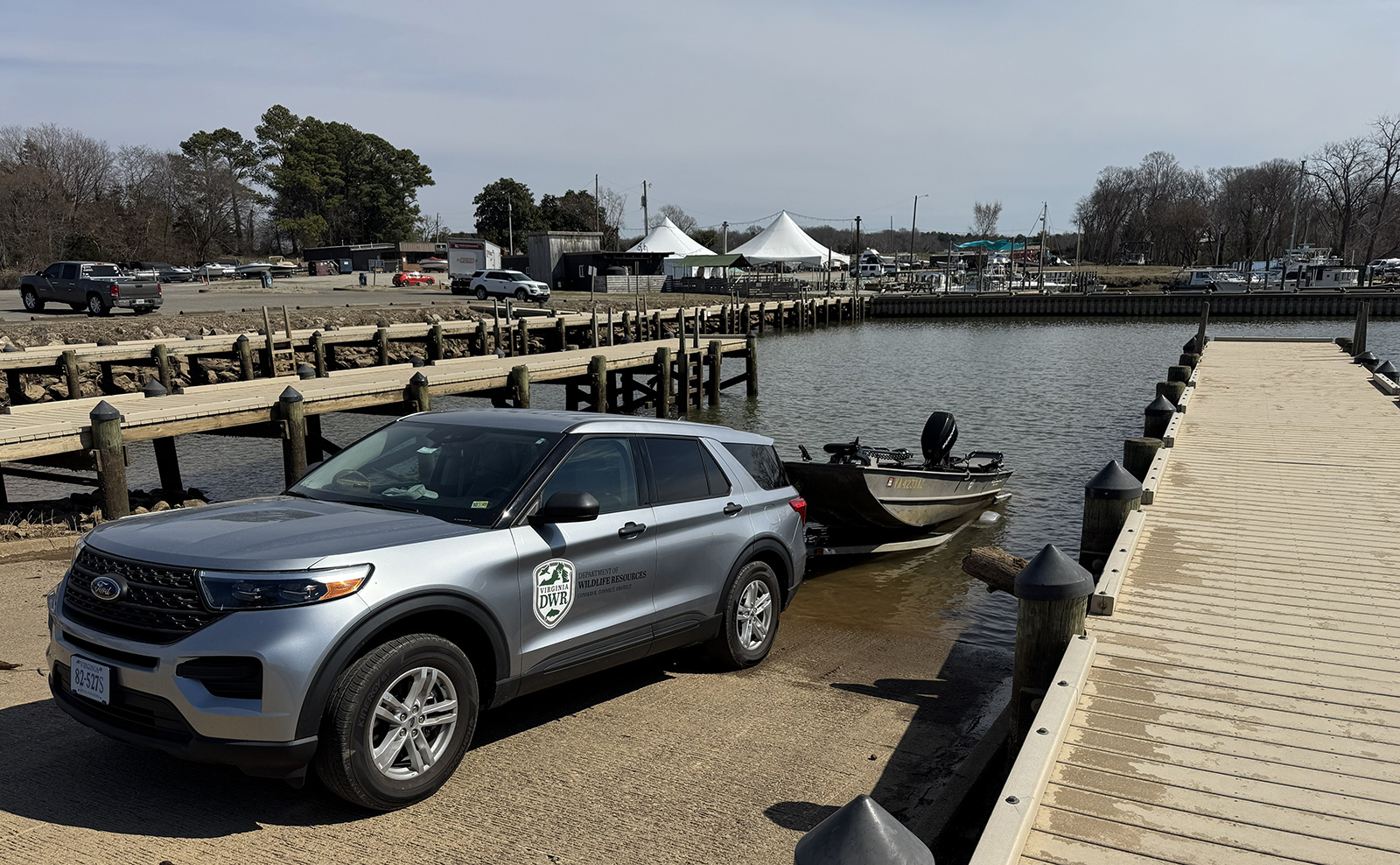 A photo of a DWR-branded vehicle backing a boat down a boat ramp into the water.