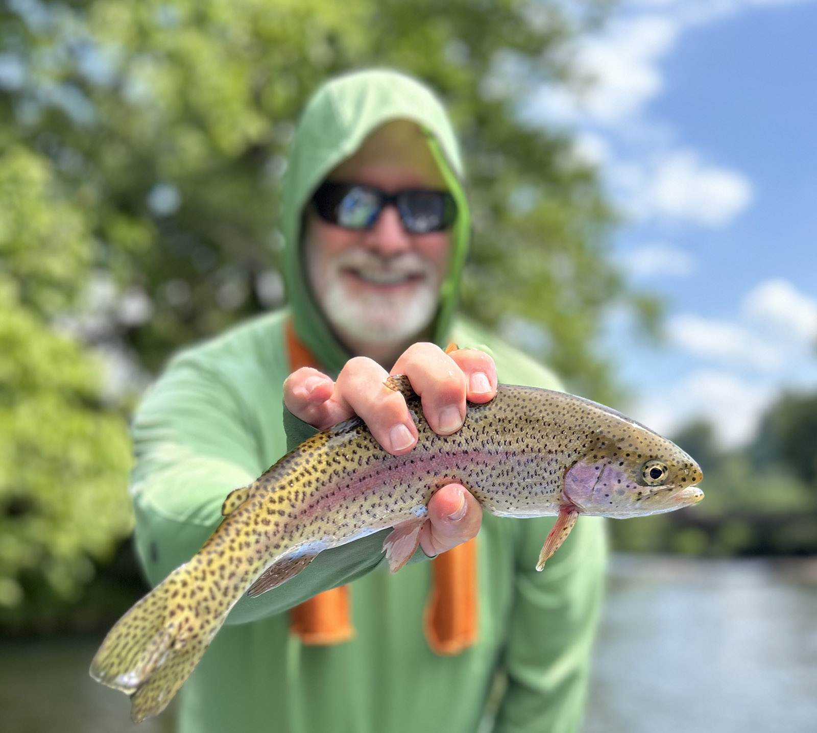 A photo of a man holding a pretty rainbow trout out of the water.