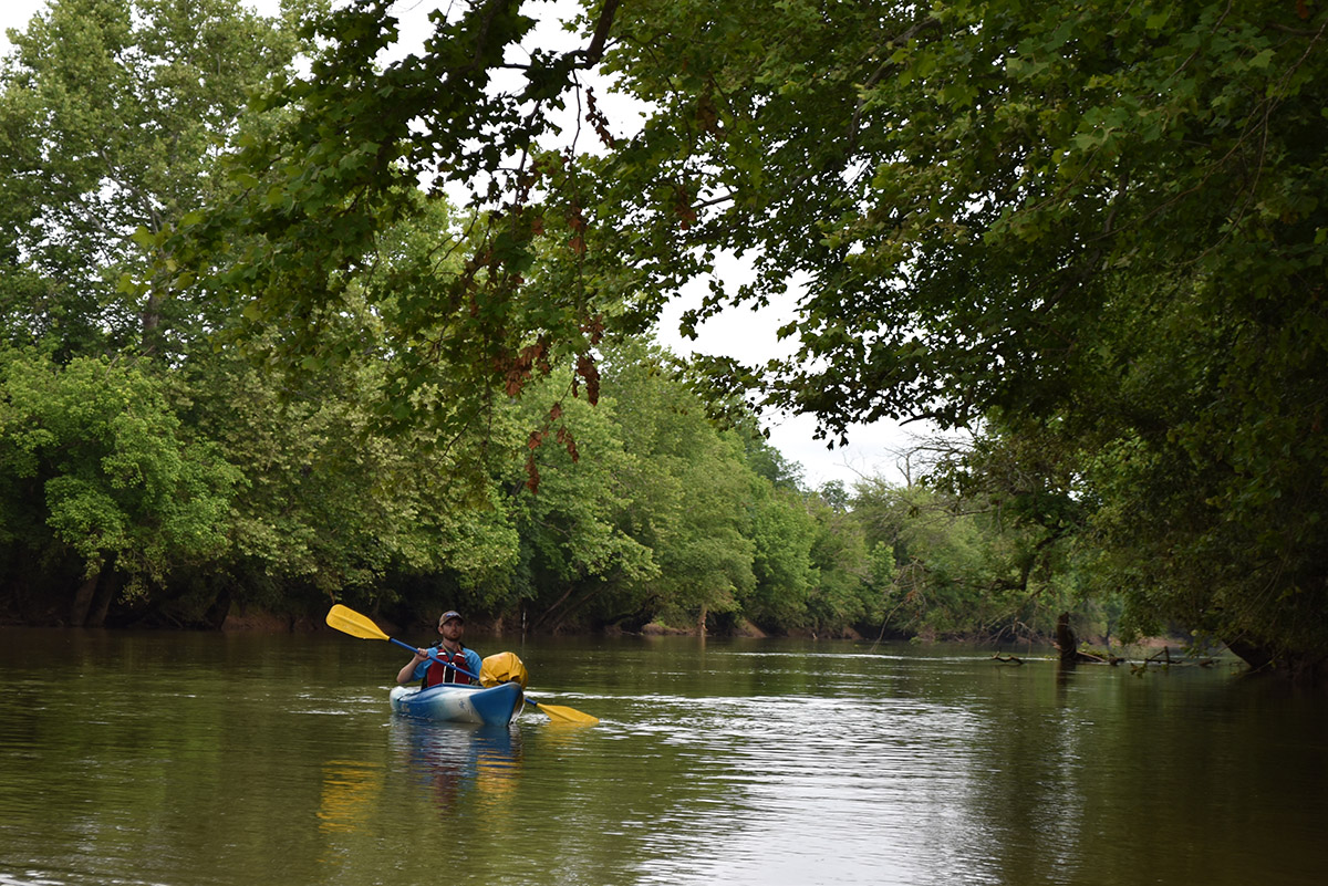 An image of a man in a blue kayak rafting along the Rappahannock