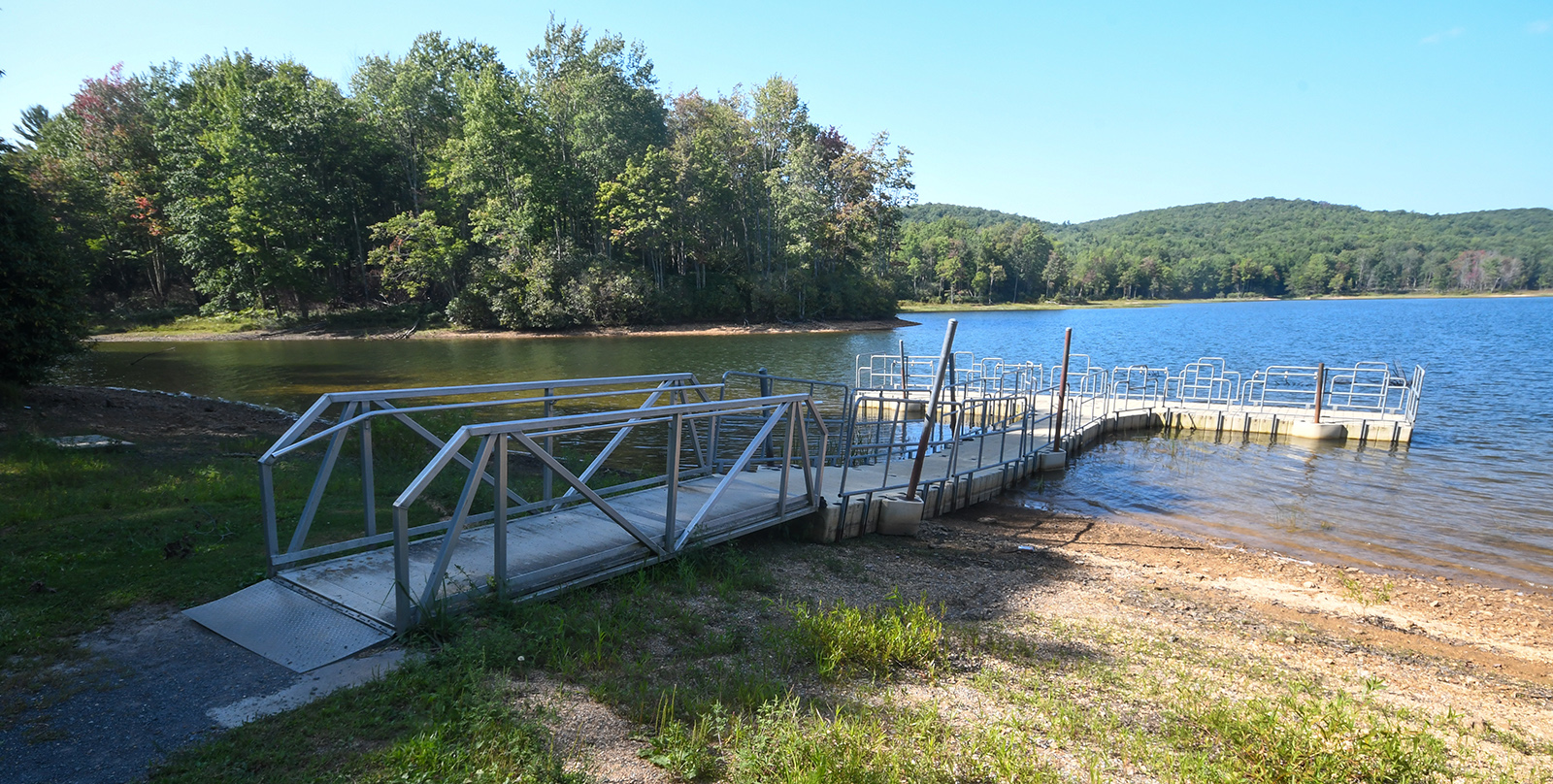 A photo of an accessible metal fishing pier projecting out onto a large lake.