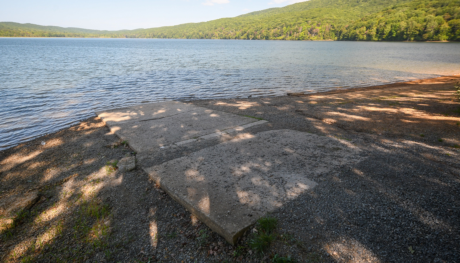 A photo of a series of concrete slabs laid on gravel leading down to the water of a lake.