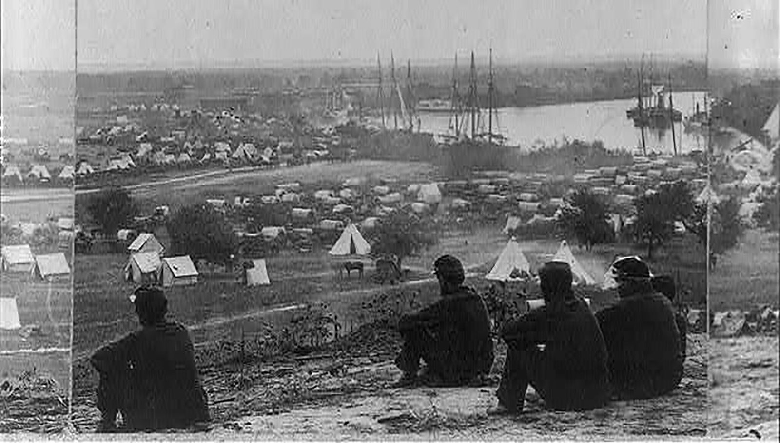 An image of four men sitting on a hill overlooking Cumberland bay outside of a military settlement during the civil war