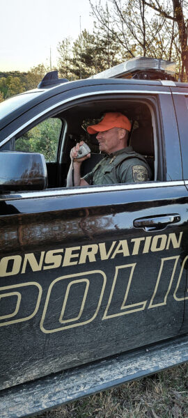 An image of a DWR conservation police officer talking into his walkie talkie within his vehicle 