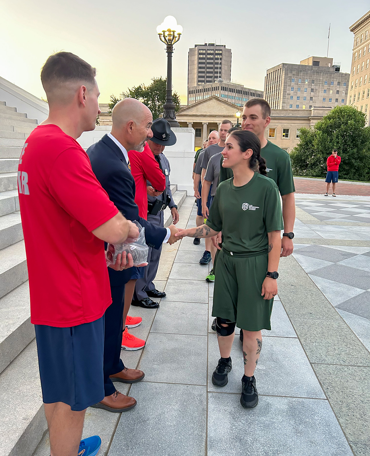 A photo of a young woman in green uniform shaking hands with a man in a suit in a receiving line.