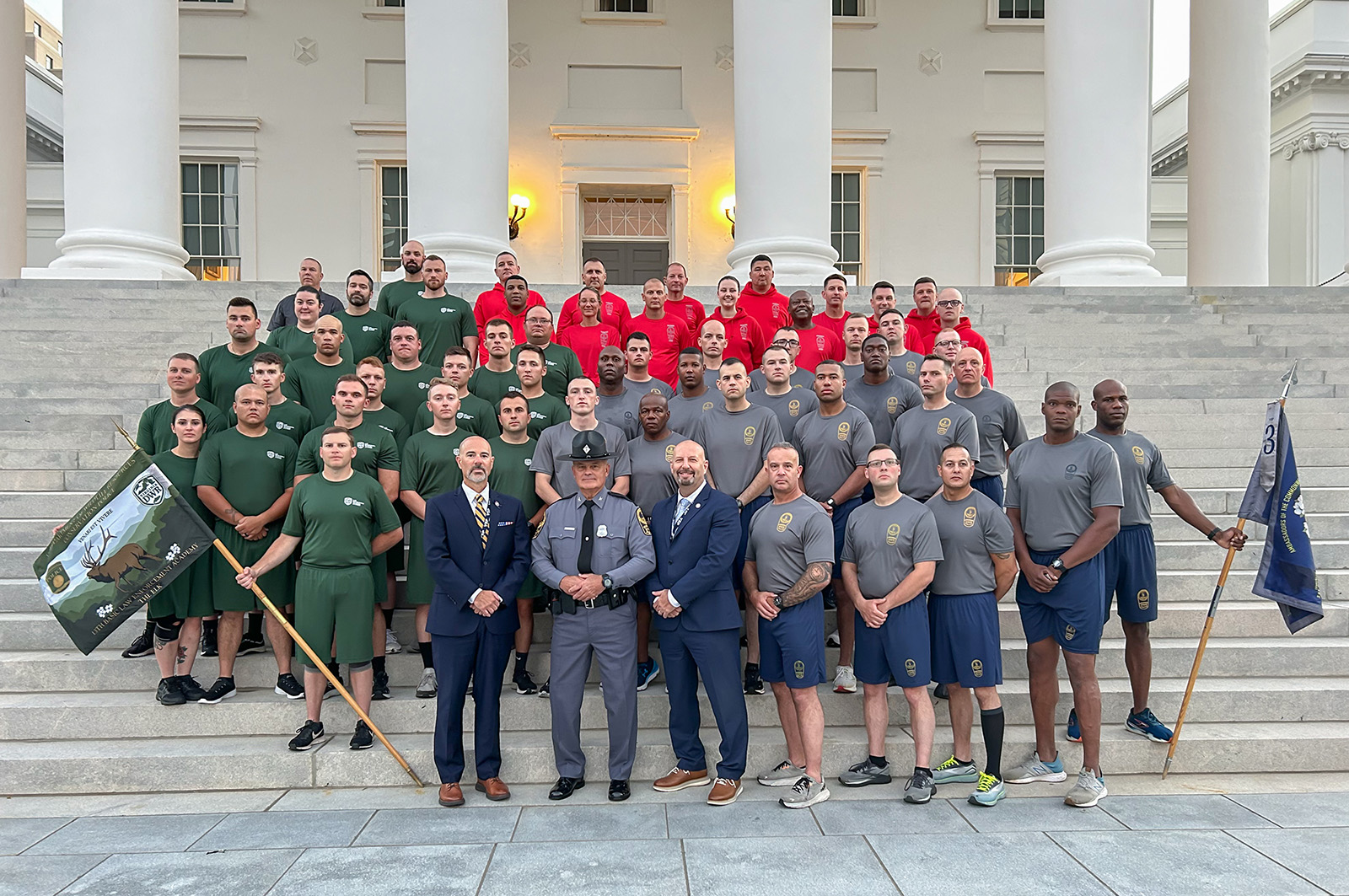 A group photo of young men and women in uniform on the steps of the Virginia Capitol building with three men in suits and uniform in the front row.