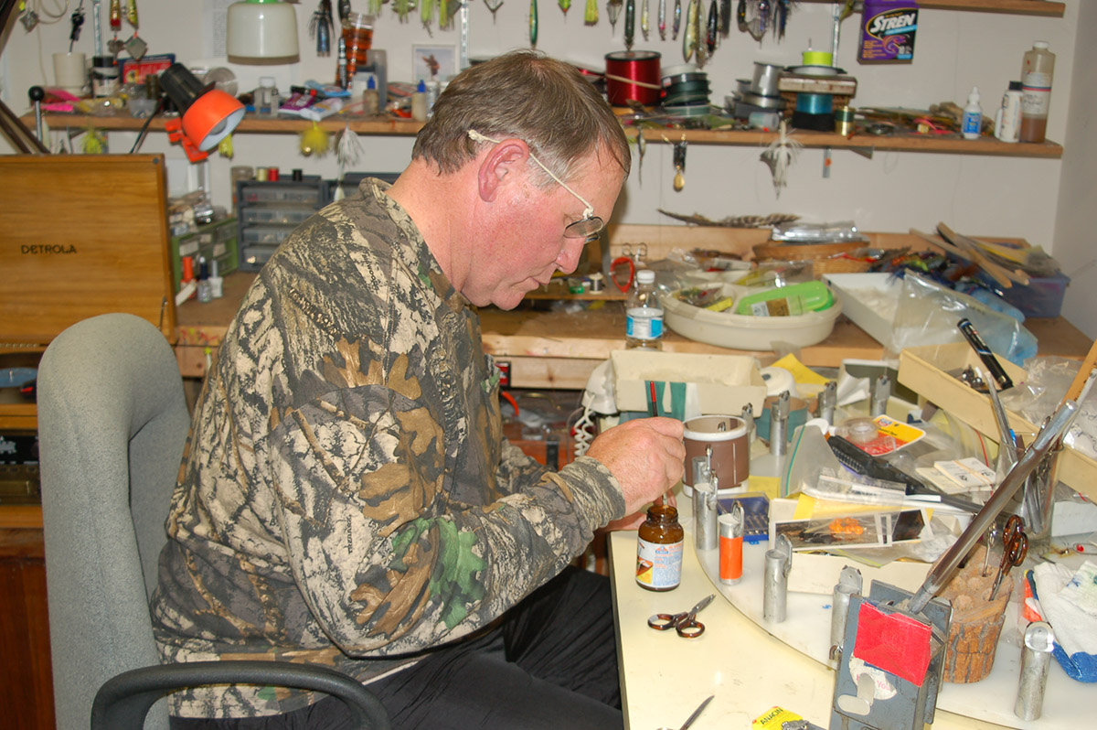 An image of a man making turkey calling devices at a bench in his home