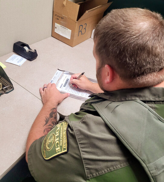 A photo of a Conservation Police Officer filling out an evidence form. 