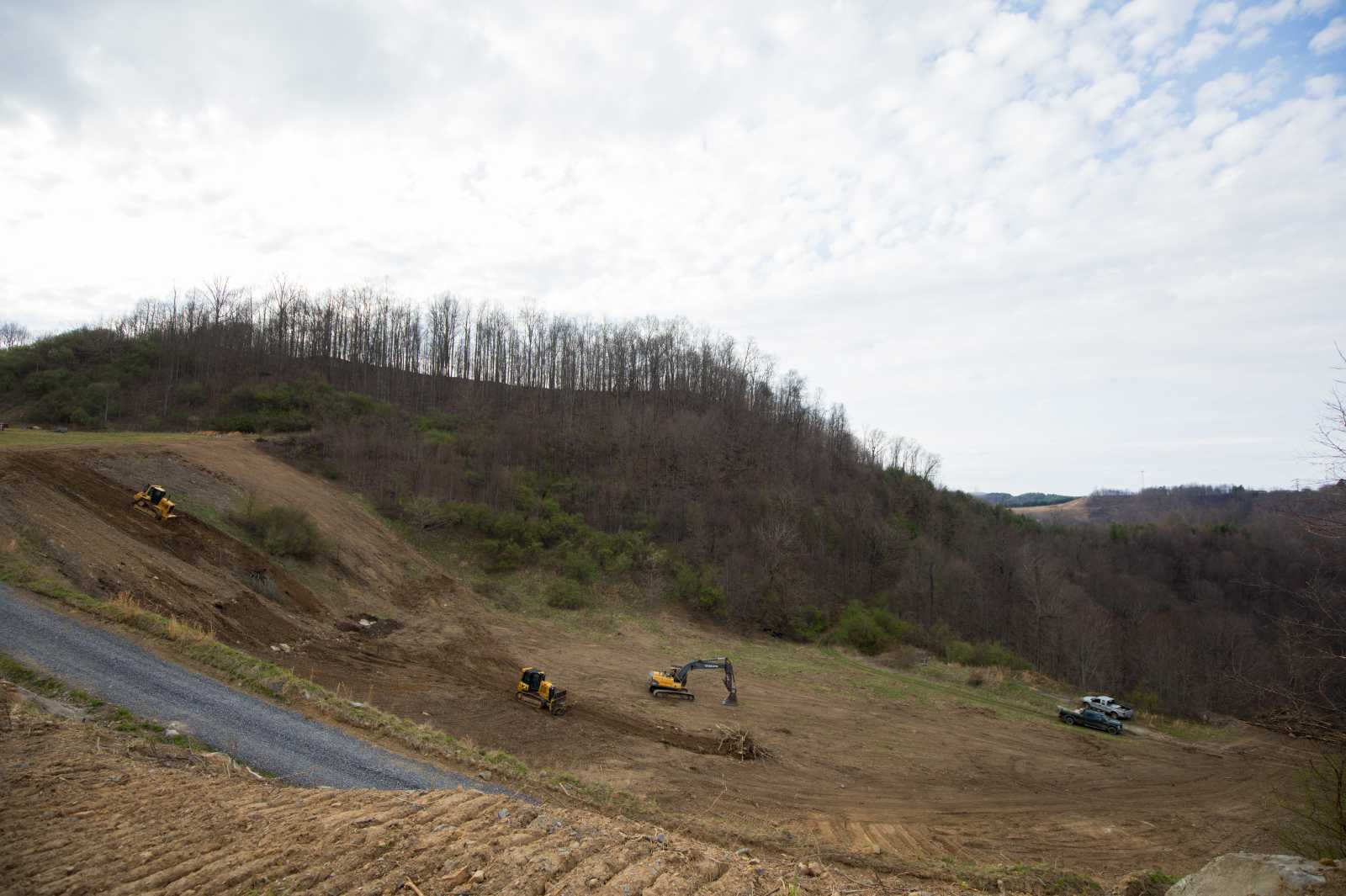 A deforested slope of mountain with heavy equipment working on it. 