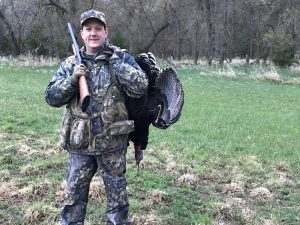 A man holding a gun holding a dead turkey