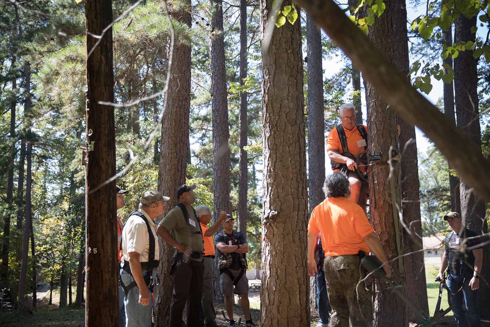 Hunter education instructors outdoors demonstrating tree stand safety to a class